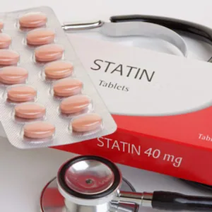 Statin tablets next to a stethoscope and medicine packaging